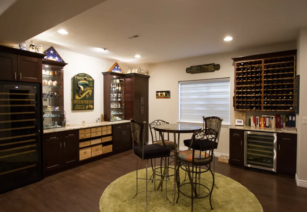 IMG_0044_1449x1000-e86f06f2-1920w Littleton vintage basement remodel. Custom shelving and cabinet installation, granite countertops, green rug with high top table and chairs. Hardwood floors and modern lighting.